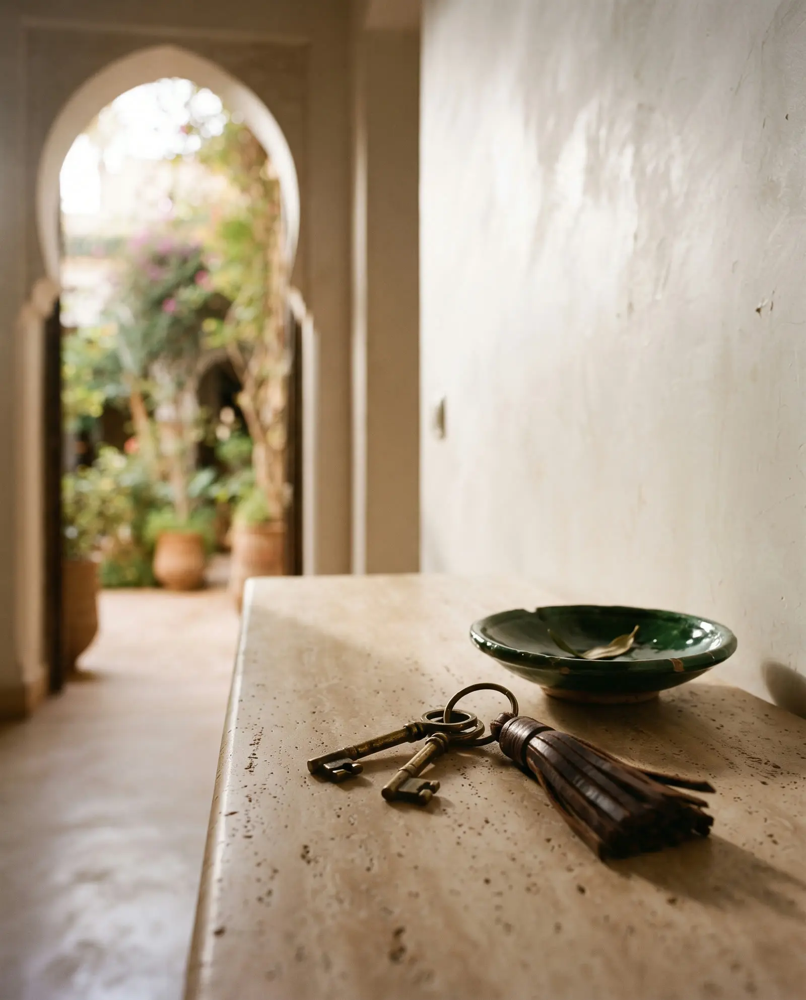 Brass keys on a travertine console in the entrance of a villa opening onto its garden